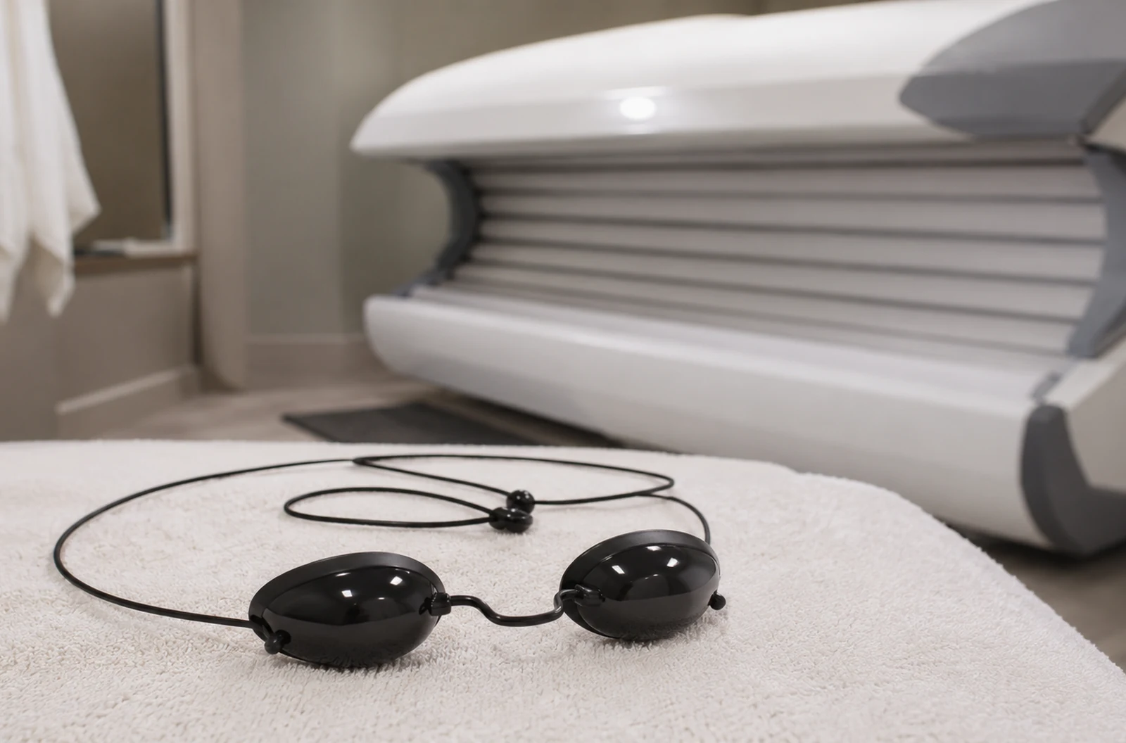 Lunettes de protection UV posées près d’une cabine de bronzage